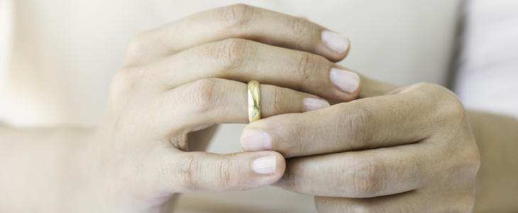 persons hand holding ring over ring finer divorce
